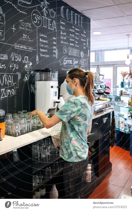 Waitress with mask cleaning glasses waitress placing dish towel face mask coronavirus written blackboard coffee maker coffee machine reviewing coffee shop