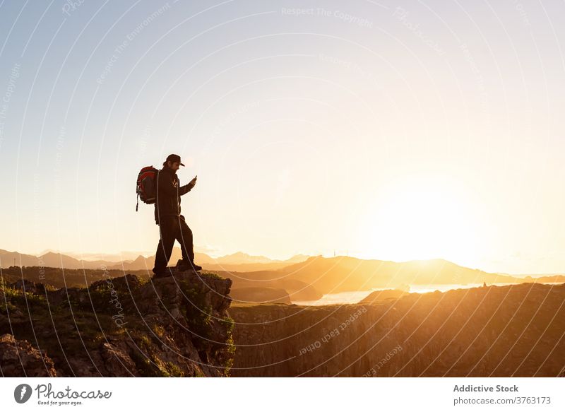 Traveling man taking picture of sunset on smartphone traveler hill take photo using explorer backpack adventure male rocky spectacular landscape nature memory