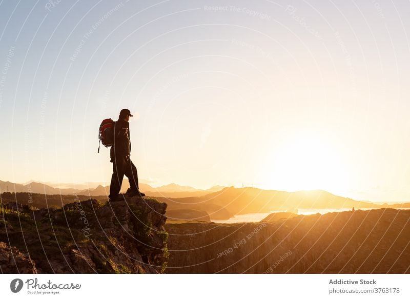 Unrecognizable traveling man on hill at sunset hiker backpack mountain admire vacation sundown trekking male rock amazing relax chill adventure scenic landscape
