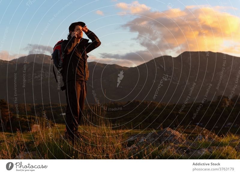 Male hiker with backpack in highland valley traveler hill man mountain admire explore sunset sky vacation sundown ridge landscape scenic rock majestic guy