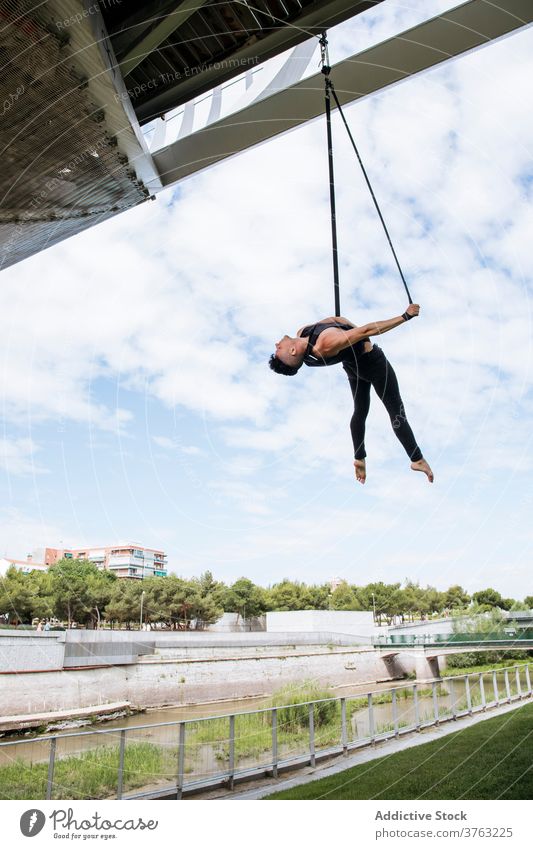 Flexible man training on aerial straps gymnast gymnastic hang perform flexible fit park male workout exercise energy athlete sport healthy sportswear effort