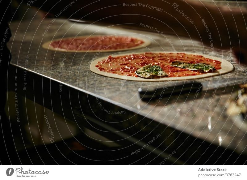 Preparation of pizza with tomato sauce dough prepare food cook kitchen ingredient raw leaf herb thin restaurant marble cuisine meal culinary italian lunch