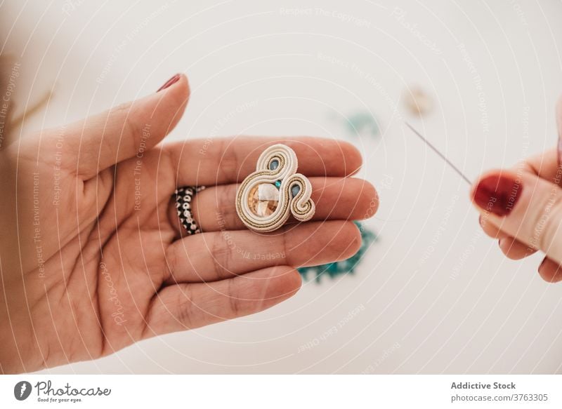 Unrecognizable artisan making soutache earrings in studio bijouterie woman create handmade workshop process craft creative handicraft female thread bead hobby
