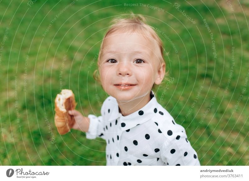 Cute and funny little girl with bun in her hand and smiling with a diffused green grass background. selective focus cute kid joy spring child smile portrait
