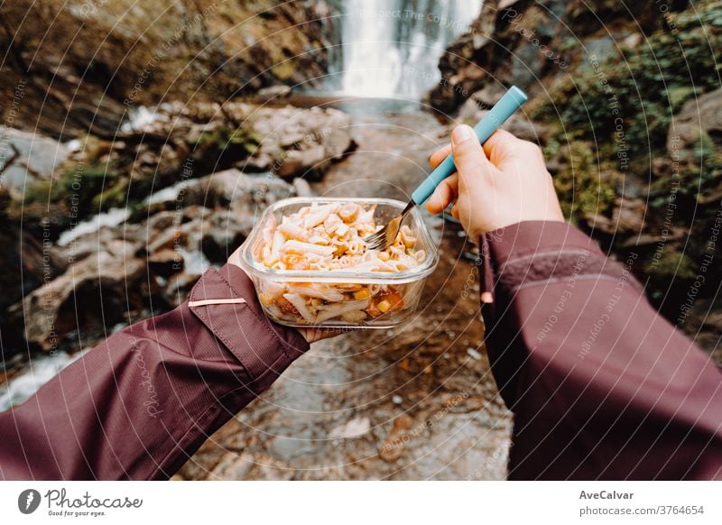 A point of view shot of a female hiker eating in front of a waterfall cook survival picnic ravenous people backpacking relaxation group camp tent bottle forest