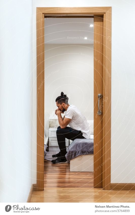 Hispanic man isolated in a room. He looks thoughtful. stressed 1 problem pain loss floor indoor dark lifestyle worry victim copy space crisis concept alone
