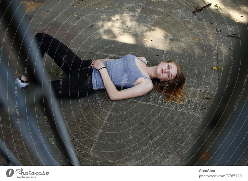 Portrait of a young woman lying on the floor behind a sliding gate Woman Young woman Slim already athletic Blonde youthful 18-25 years red blonde hair look see