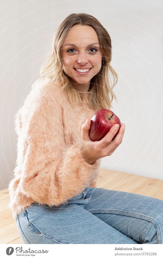 Cheerful woman with apple in kitchen fresh healthy food delicious delight vitamin fruit home female table happy joy diet organic domestic pleasure ripe enjoy