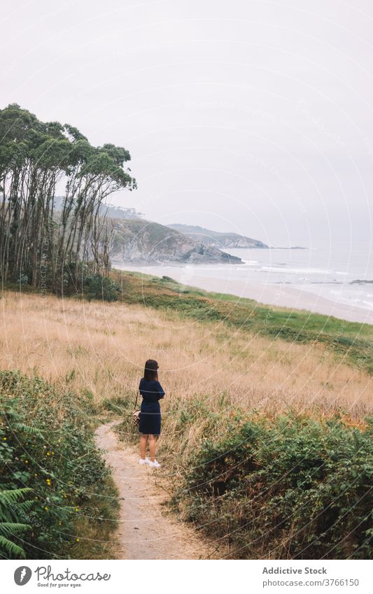 Woman standing on path at seaside woman lonely overcast coast gloomy alone shore female travel tourism spain asturias frejulfe beach contemplate cloudy dull