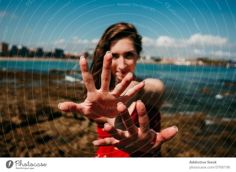Smiling woman showing hands to camera grace reach out gesture seashore charming content demonstrate female sunny summer holiday coast beach happy stand pleasure