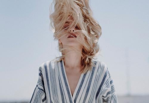 Portrait of a caucasian blonde woman.  She is shaking her head with the hairs covering her face. shake fashion lifestile conceptual Caucasian