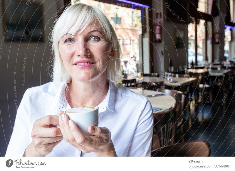 Young blonde woman drinking coffee in cafe person sitting cup female lifestyle table smiling business girl young indoor happy adult beautiful smile one person