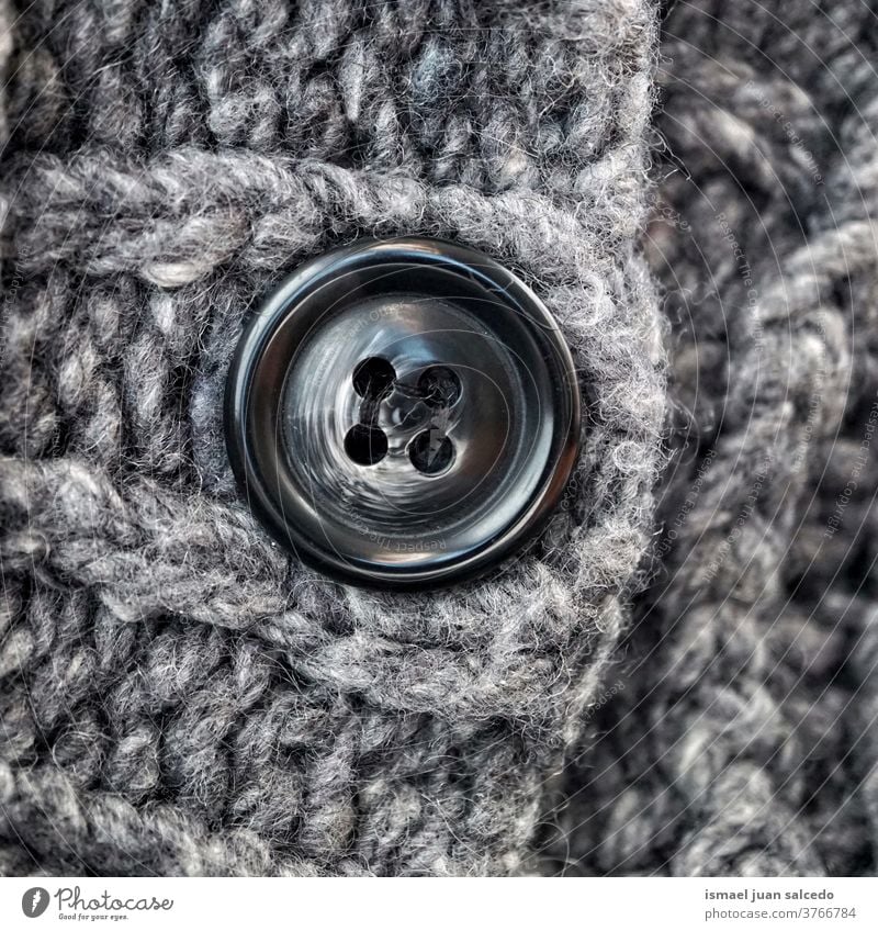 black button in gray wool, grey background thread fabric cloth textured abstract pattern material industry textile design handmade detail macro knitting