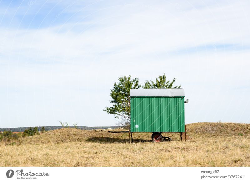 A small green pendant stands on a grassy lawn and waits for its lovers' tryst Site trailer Trailer Exterior shot Colour photo Lawn dry grassland Deserted grazed