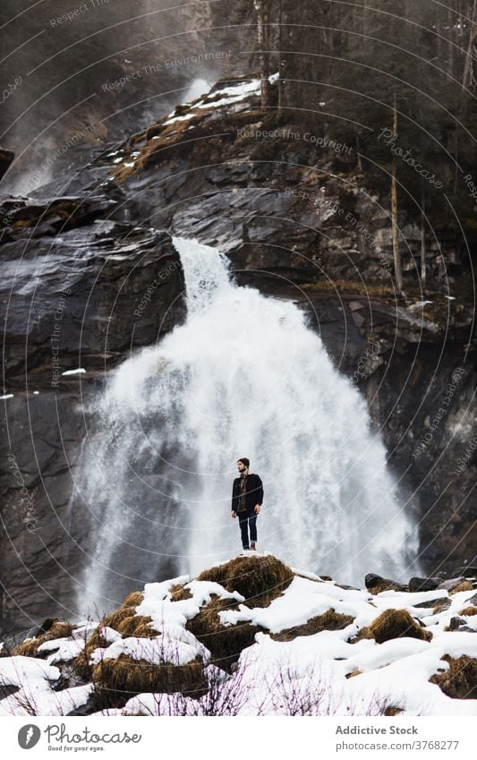 Traveling man near waterfall in mountains traveler winter highland hiker nature landscape stream male germany austria snow adventure hill trip journey tourism
