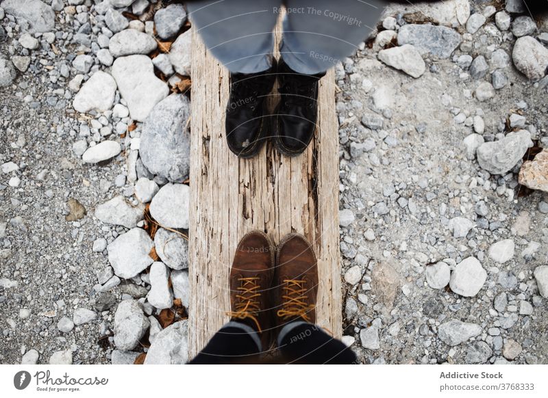 Couple of hikers standing on wooden log traveler couple leg boot together stone nature weathered shabby adventure timber lumber tourism rough footwear