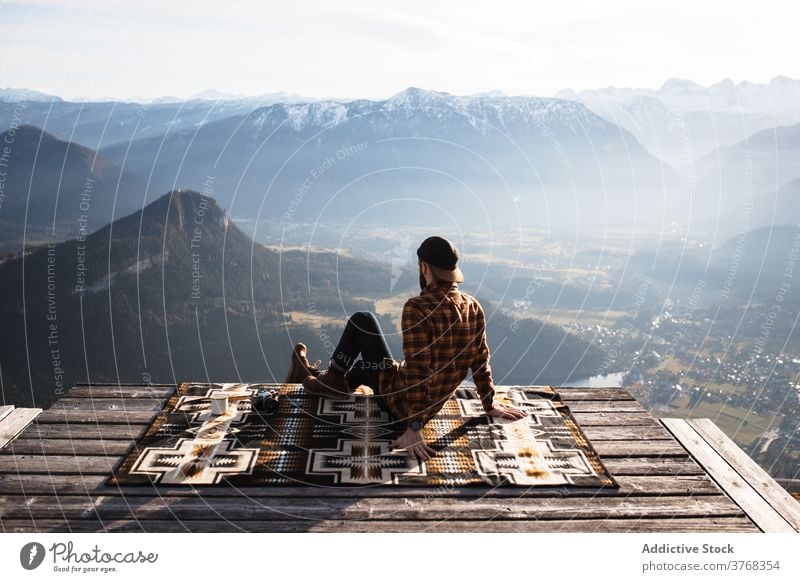 Traveling man sitting on hill and admiring view of mountains viewpoint traveler tourist landscape scenery ridge morning relax male germany austria nature