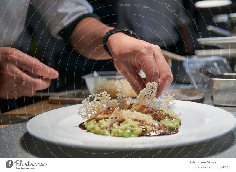 Crop chef cooking Risotto in kitchen risotto rice garnish restaurant savory chip delectable crispy culinary plate fresh food meal dish serve tasty cuisine