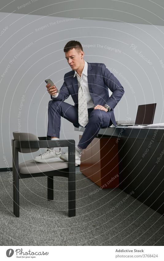 Stylish businessman on cellphone in office smartphone sit table using entrepreneur style male workplace chair occupation device gadget busy job professional