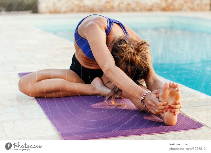 Young woman practicing stretching in Head to Knee pose Yoga pool Concentration Relaxation Female garden health Spirituality Balance Happiness Nature Caucasian