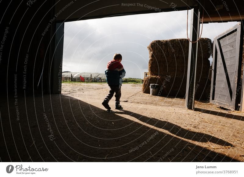 Boy leaves barn on farm Boy (child) Child Farm Shadow Hay Hay bale Barn chill Summer vacation cloudy sky Netherlands Sunlight lost in thought brood undecided