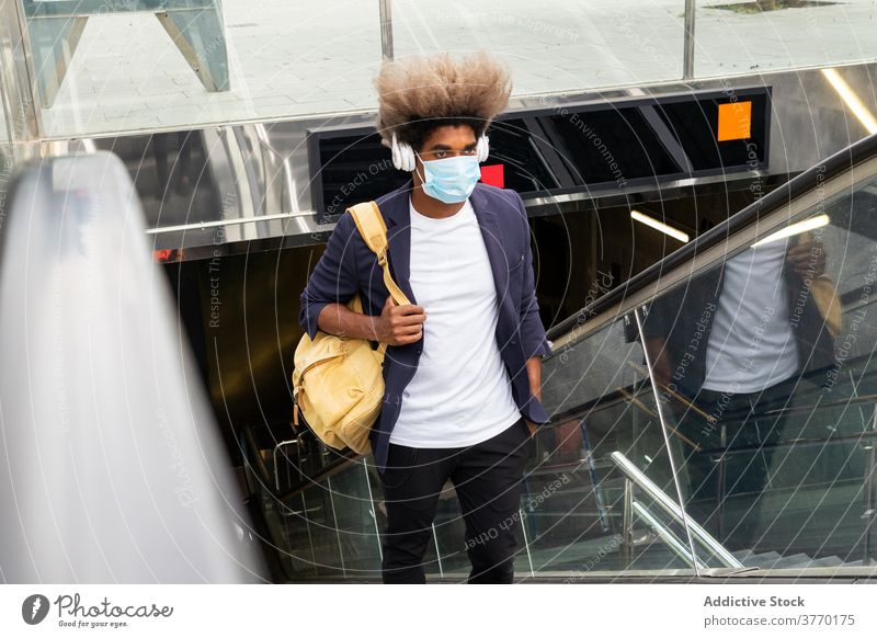 African man wearing a mask on an escalator with a bag while list epidemic coronavirus pandemic protective safety health tourist underground metro afro ethnic