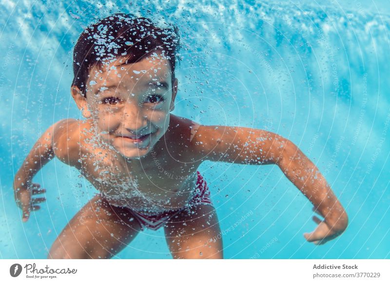 Cheerful boy in swimming pool kid dive playful delight childhood vacation summer having fun water recreation joy aqua cheerful swimsuit clear holiday pleasure