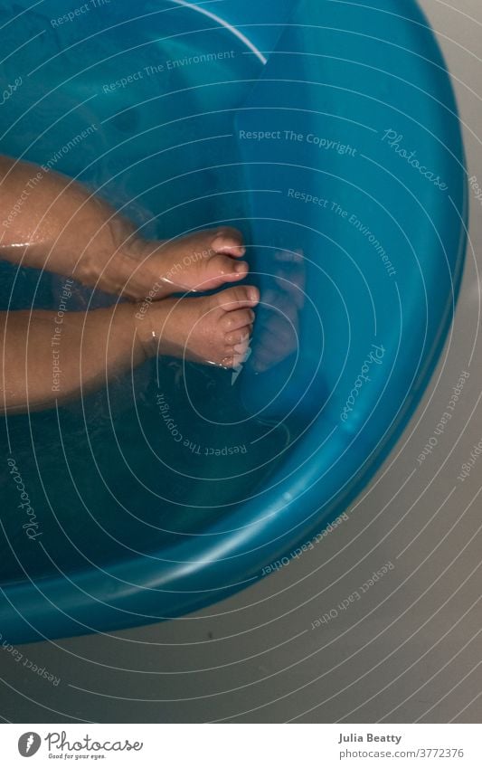 Bath time: baby bath tub with newborn, reflection of toes and feet in water bath time clean infant child 0 - 12 months infancy childhood small cute relaxed