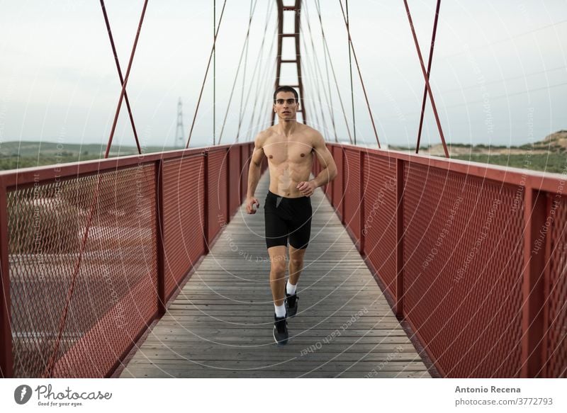 Shirtless runner training on red bridge man strong fit fitness footbridge footpath men male young adult one person torso muscular muscle handsome sportswear