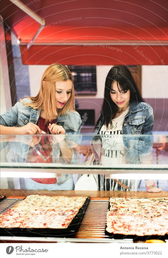 Pretty young women choosing pizza in outdoors store woman eating city food temptation meal street food fresh city life ready-to-eat cooked casual clothing