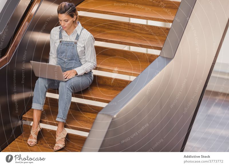 Woman sitting on stairs and working on laptop freelance woman building project modern staircase entrepreneur using female job contemporary business busy surfing