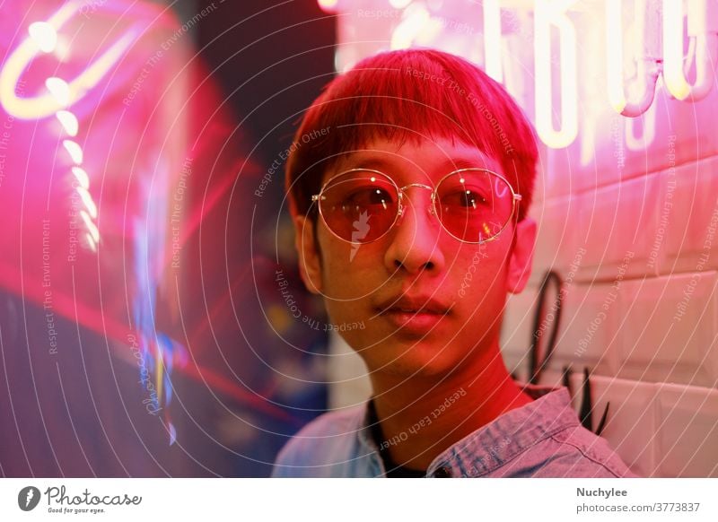 Young asian hipster millennial man in street style fashion concept and wearing sunglasses in pink neon light trend millennials gen z accessories adult art