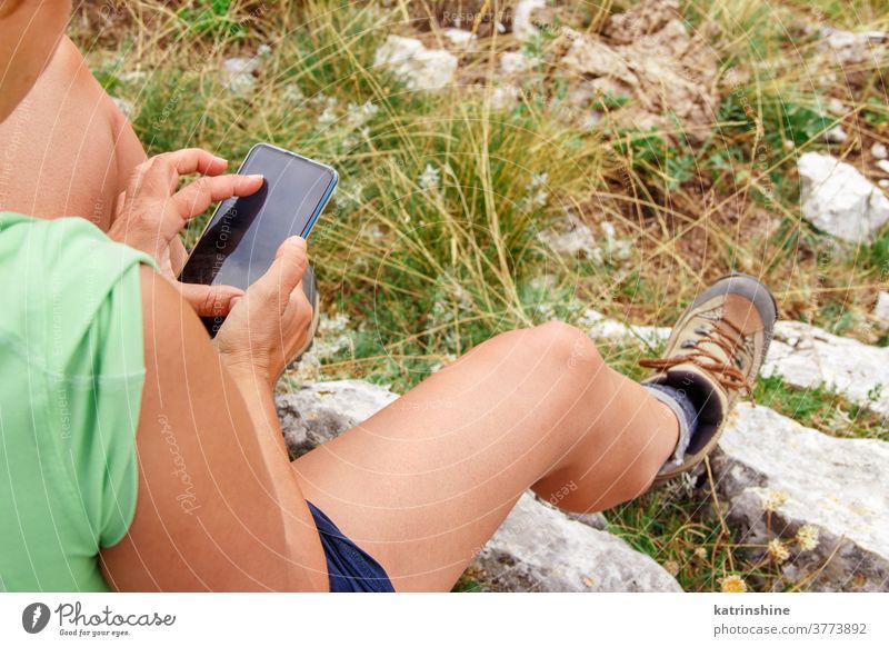 Woman uses mobile phone while hiking in the mountains Use Telephone Hiking Nature Outdoors hands Faceless acivity Touch Screen complete person travel Rest