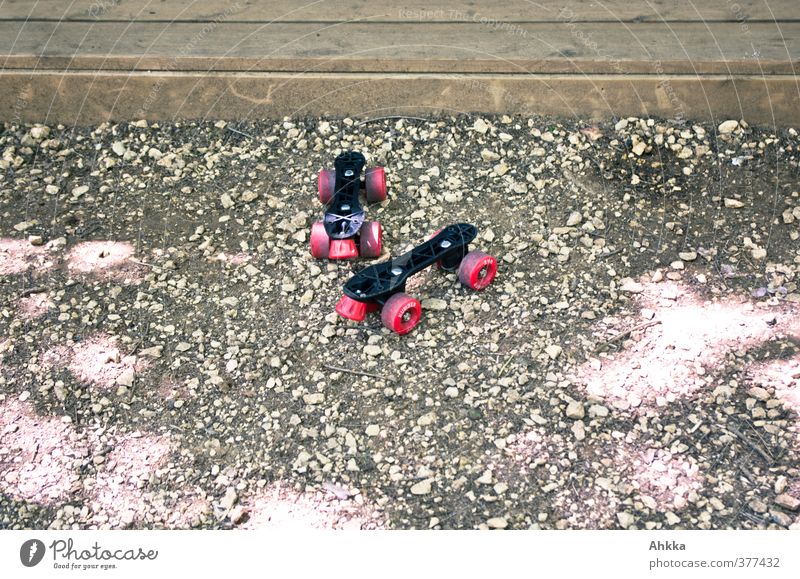 Broken roller skates with red rollers on gravel surface Design Sports Means of transport Collector's item Roller skates Discover Relaxation Driving Playing Romp