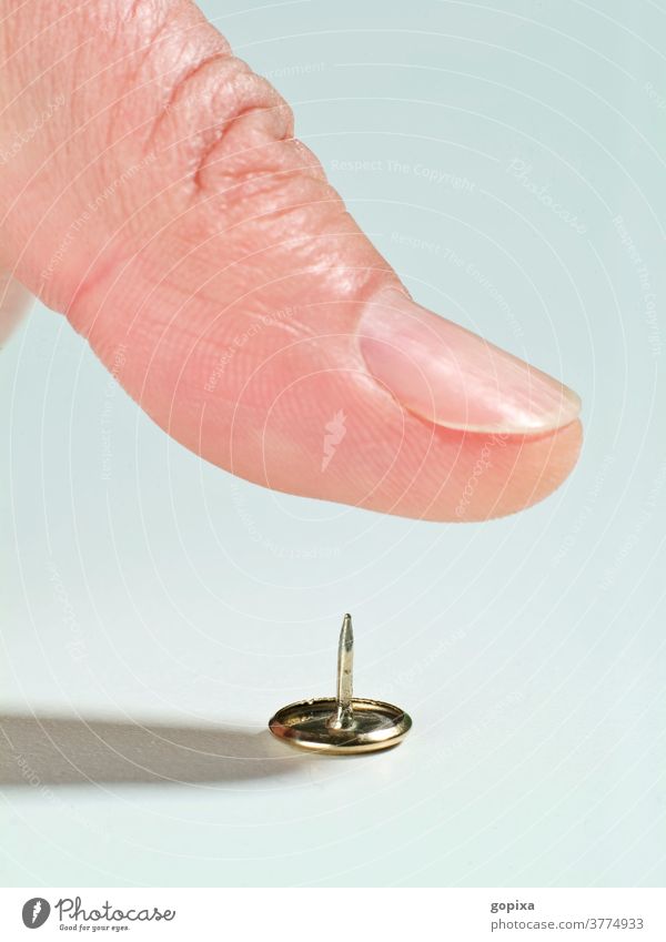 Close-up of a thumb over a thumbtack drawing pin Thumbtack Fingers peril violation Risk of injury Human being fingernails Macro (Extreme close-up) risky