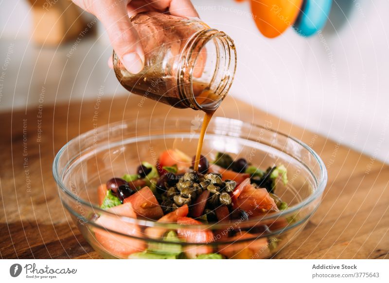 Close up of woman hands pouring dressing over a salad. vegetable vinegar balsamic fresh seasoning healthy natural food add kitchen cook prepare ingredient