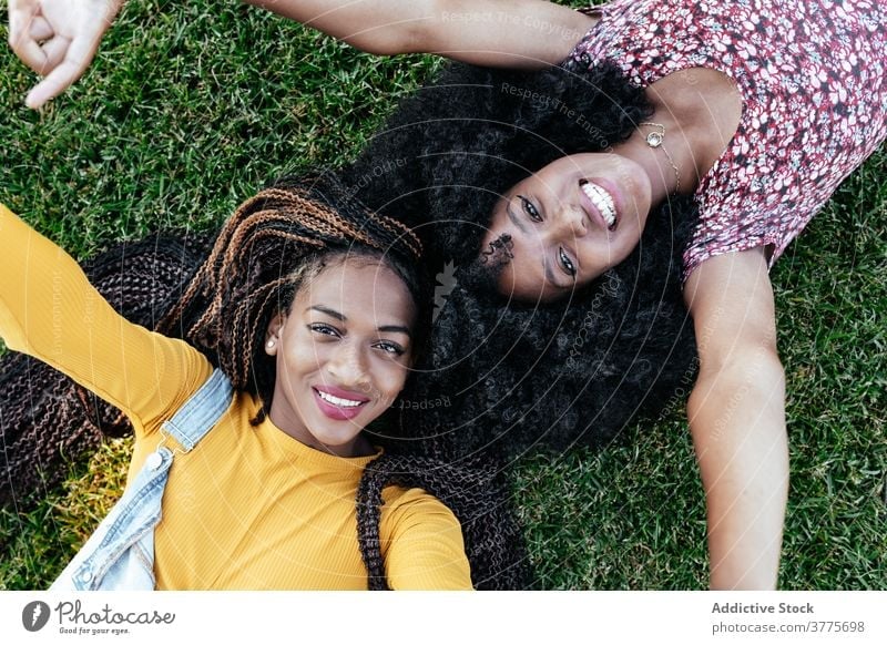 Happy black women lying on green grass friend together happy cheerful summer enjoy friendship girlfriend young african american ethnic afro female student smile