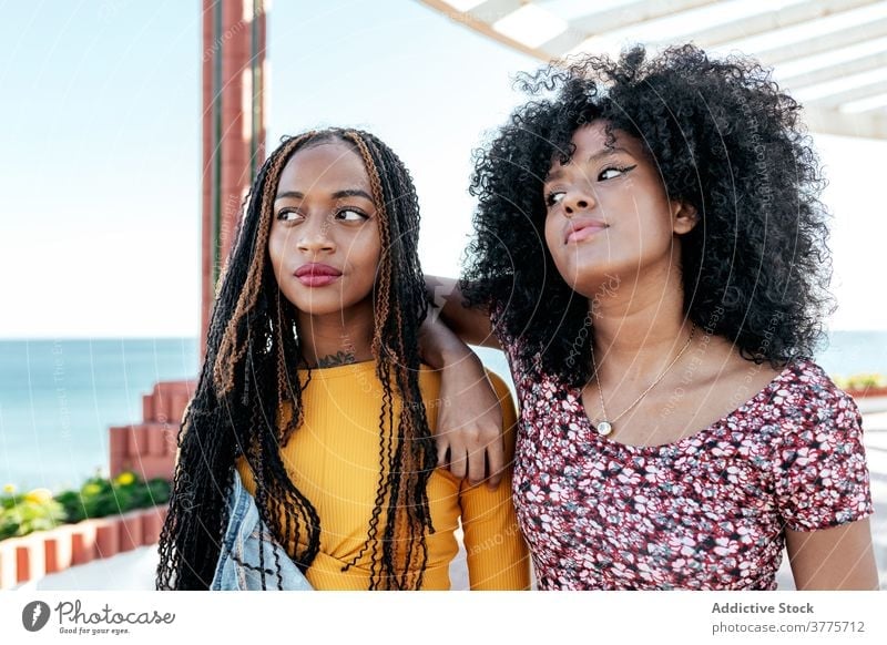 Pensive ethnic women at seafront serious best friend hug friendship pensive together thoughtful summer embankment black african american braid curly hair