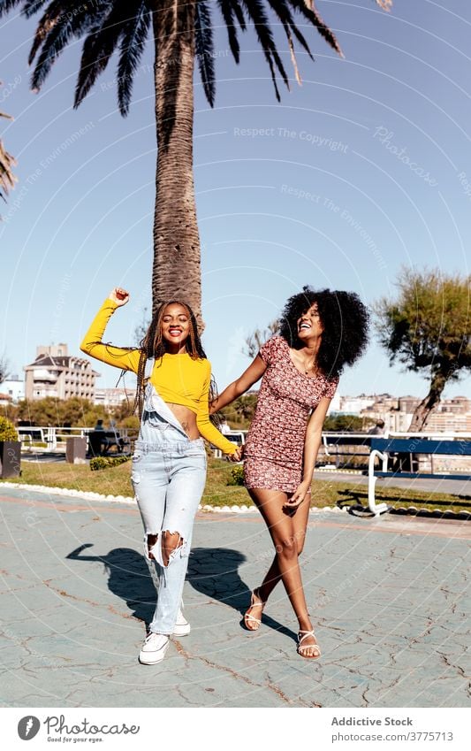Smiling black women walking along street together friend tropical delight friendship best friend summer ethnic african american happy town cheerful smile braid