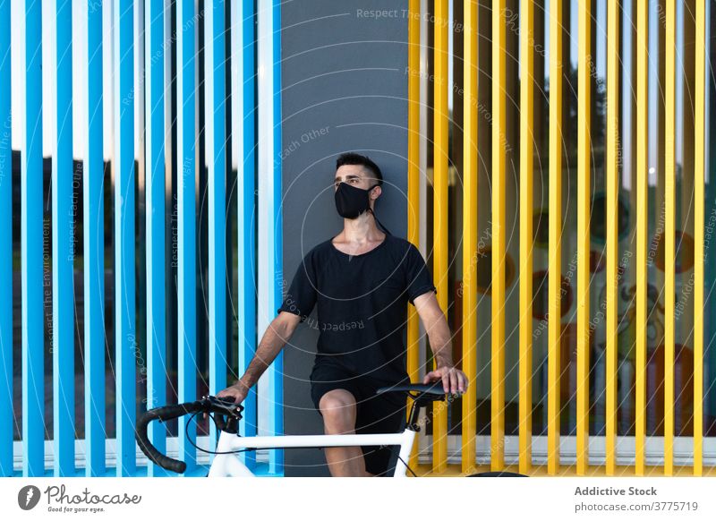 Man in mask with bicycle on street man coronavirus city protect bike vehicle epidemic male colorful building vivid vibrant bright urban town transport guy