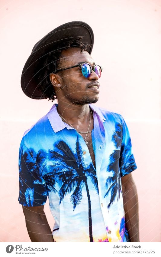 Stylish black man in hat and sunglasses in city shirt palm tree print trendy style confident determine handsome male ethnic african american street building