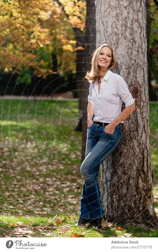 Smiling woman near tree in park - a Royalty Free Stock Photo from Photocase