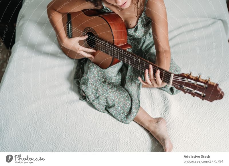 Woman playing guitar in bedroom guitarist music woman cheerful laugh talent entertain carefree instrument female ethnic acoustic cozy home happy musician