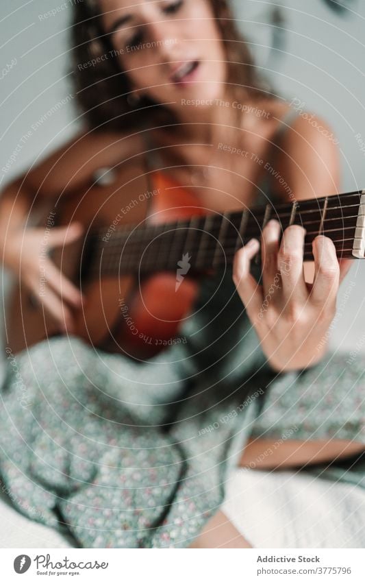 Positive woman playing guitar in bedroom guitarist music cheerful laugh talent entertain carefree instrument female ethnic acoustic cozy home happy musician