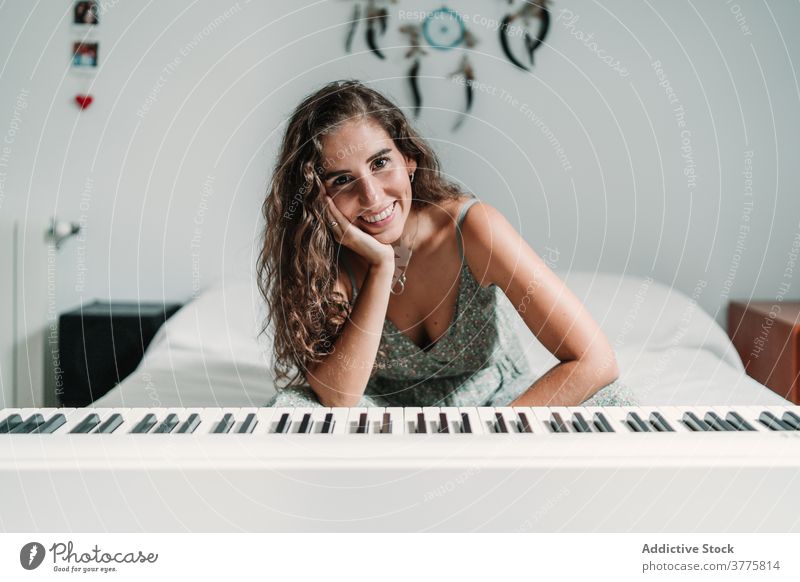 Woman with modern synthesizer at home electric piano woman musician relax sound bed female ethnic melody rest cozy sit song lean peaceful lean on hand lady