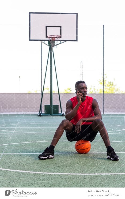 Ethnic basketball player talking on smartphone on court sportsman playground sports ground using relax summer male ethnic black african american tall speak call