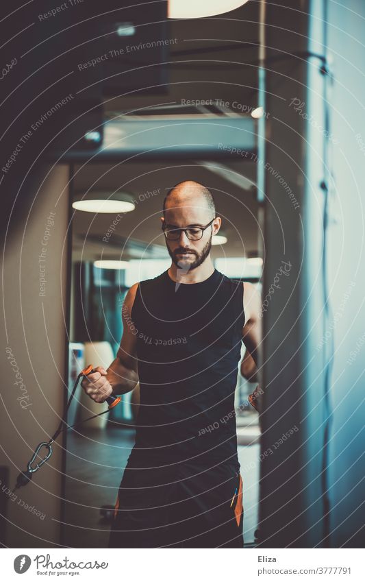 A man with a beard and glasses doing weight training at the gym Fitness centre Rowing Effort Sports Weight training Muscular Facial hair Eyeglasses workout Body