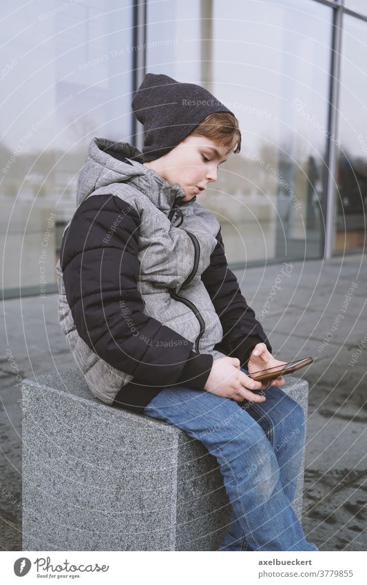 7 year old boy playing with smartphone outdoors in winter child kid mobile cell technology game gaming little people young internet childhood lifestyle person