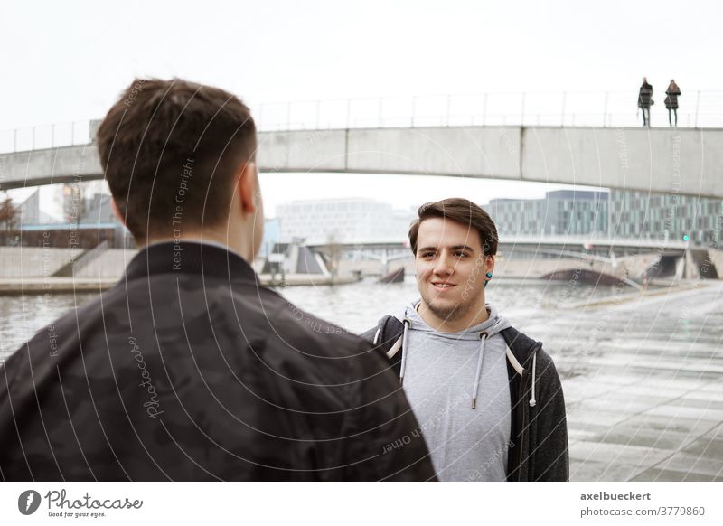 two male teenage friends having a conversation by the river people real people talking lifestyle candid authentic man men smiling friendship young casual adult