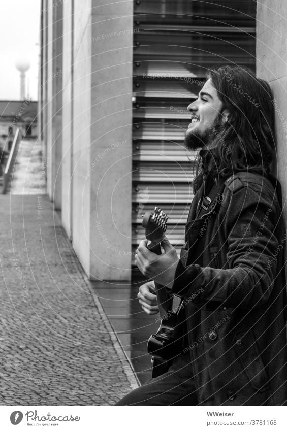 A young musician sings in the government district of Berlin and plucks his guitar Music Musician Guitar Bass guitar Song street music Meditative sad